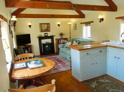 a kitchen and living room with a table and a couch at The Piggery in St Austell