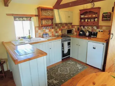 a kitchen with white cabinets and a stove top oven at The Piggery in St Austell