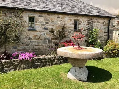 a bird bath in front of a stone house at The Piggery in St Austell