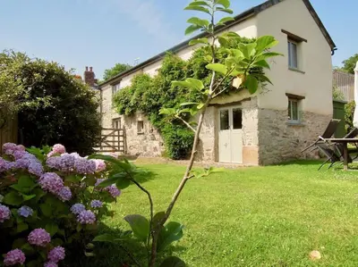 a cottage with a garden and flowers in front of it at The Oxen House in St Austell