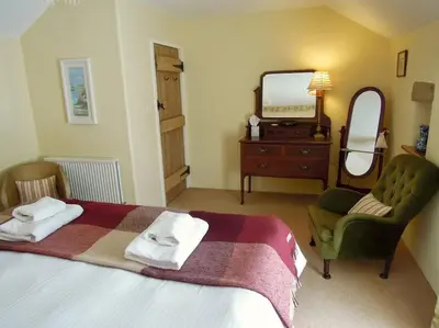 a bedroom with a bed and a mirror and a chair at The Oxen House in St Austell