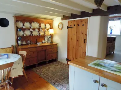 a kitchen with a table and a cabinet with plates on it at The Oxen House in St Austell
