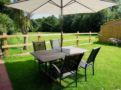 a wooden table with chairs and an umbrella at The Oxen House in St Austell