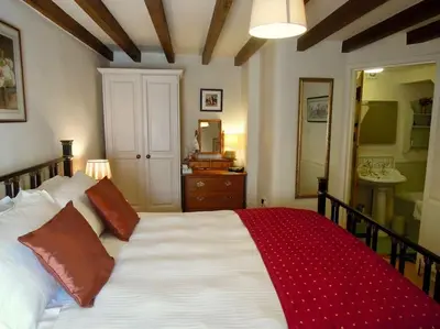 a bedroom with a large white bed with a red blanket at The Stables - Nanjeath in St Austell
