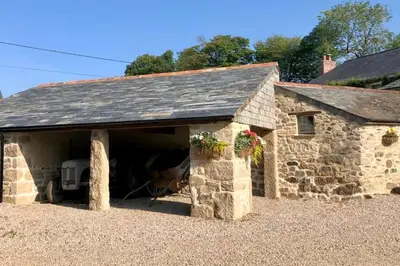 a stone barn with a car garage at The Stables - Nanjeath in St Austell