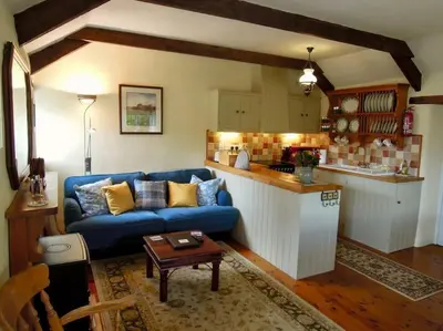 a living room with a blue couch and a kitchen at The Stables - Nanjeath in St Austell