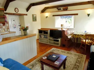 a living room with a blue couch and a tv at The Stables - Nanjeath in St Austell