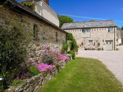 a stone building with flowers in front of it at The Stables - Nanjeath in St Austell