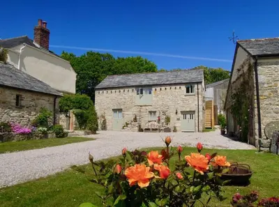 an old stone house with orange flowers in the yard at The Stables - Nanjeath in St Austell