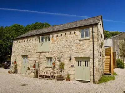 a stone building with two garage doors and a bench at The Granary in St Austell
