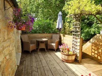 a patio with a table and an umbrella and flowers at The Granary in St Austell