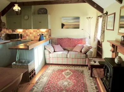 a living room with a couch and a kitchen at The Granary in St Austell