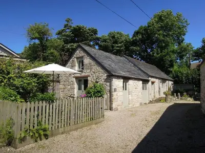 a stone building with an umbrella next to a fence at The Cider Barn in St Austell