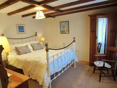 a bedroom with a bed and a table and a chair at The Cider Barn in St Austell