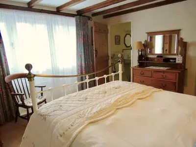 a bedroom with a bed and a dresser and a window at The Cider Barn in St Austell