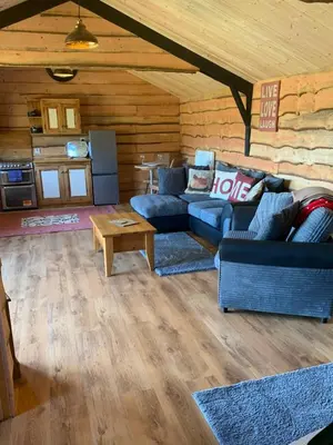a living room with blue couches and a table at Brook lodge 2 in Liskeard