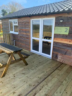 a wooden cabin with a picnic table and a bench at Brook lodge 2 in Liskeard