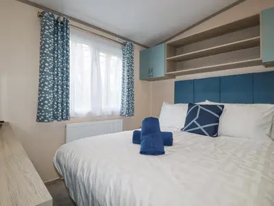 a bedroom with a large white bed with blue curtains at The Mermaid A04 in Par