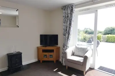 a living room with a tv and a chair at Two Bedroomed Holiday Cottage with Sea Views in St Austell