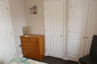 a bedroom with a dresser and a white door at Two Bedroomed Holiday Cottage with Sea Views in St Austell