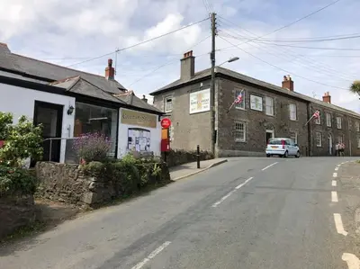 a street in a small town with a car parked on the road at Two Bedroomed Holiday Cottage with Sea Views in St Austell