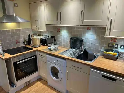 a kitchen with a sink and a washing machine at Two Bedroomed Holiday Cottage with Sea Views in St Austell