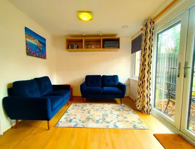 a living room with two blue chairs and a rug at Woodland View - Families & Pets in Uny Lelant