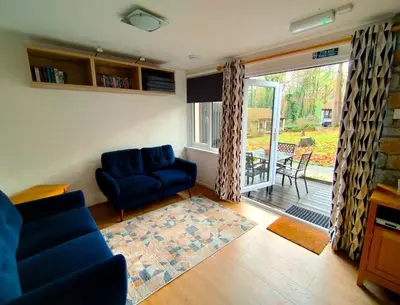 a living room with a blue couch and a sliding glass door at Woodland View - Families & Pets in Uny Lelant