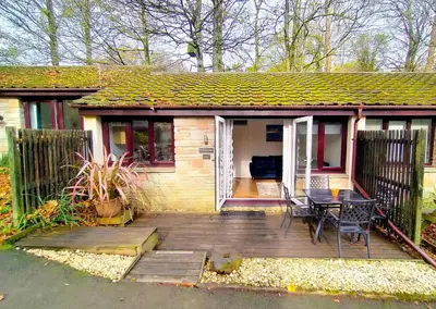 a small house with a wooden deck with a table at Woodland View - Families & Pets in Uny Lelant