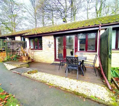 a house with a wooden deck with a table and chairs at Woodland View - Families & Pets in Uny Lelant