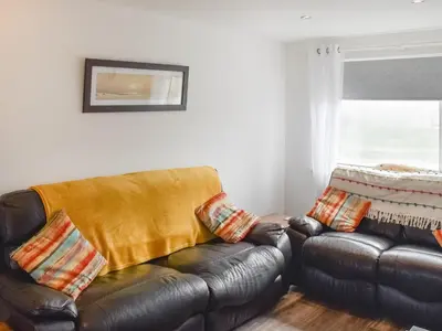 a living room with a leather couch and a window at Beach House in Perranporth