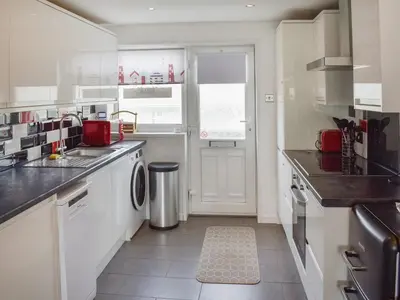 a white kitchen with a sink and a dishwasher at Beach House in Perranporth