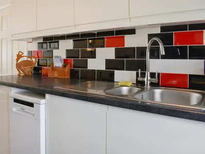 a kitchen with a sink and red and black tiles at Beach House in Perranporth