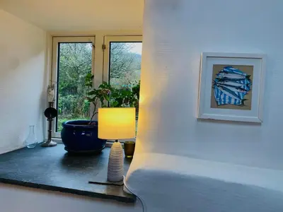 a table with a lamp and a picture on a wall at Cosy Barn A rural location near Tintagel in Tintagel