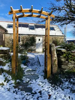 a wooden arch in a snow covered yard at Cosy Barn A rural location near Tintagel in Tintagel