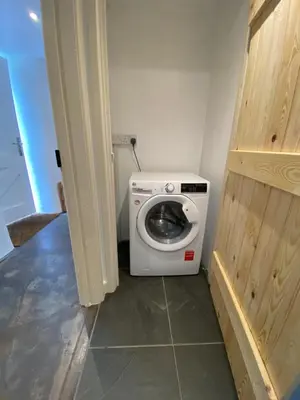 a bathroom with a washing machine in a room at Cosy Barn A rural location near Tintagel in Tintagel