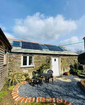 a stone house with solar panels on the roof at Cosy Barn A rural location near Tintagel in Tintagel