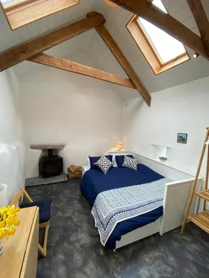 a bedroom with a blue bed in a attic at Cosy Barn A rural location near Tintagel in Tintagel