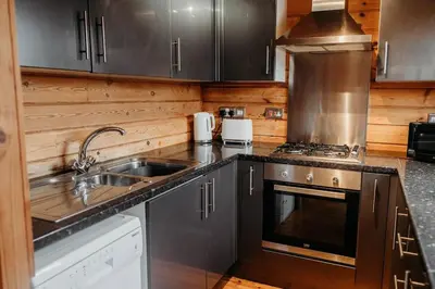 a kitchen with a sink and a stove at Finlodge- Pet-Friendly Scandinavian Cabin in Callington
