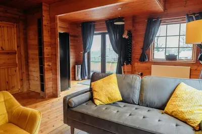a living room with a couch and some windows at Finlodge- Pet-Friendly Scandinavian Cabin in Callington