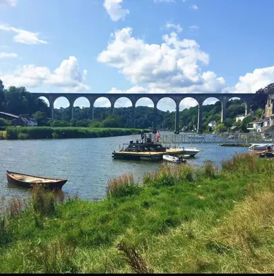 a group of boats on a river with a bridge at Woodpecker Lodge- A Pet Friendly Rural Retreat in Callington