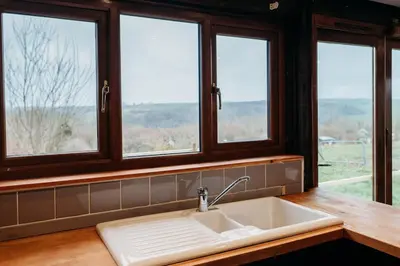 a kitchen with a sink and four windows at Woodpecker Lodge- A Pet Friendly Rural Retreat in Callington