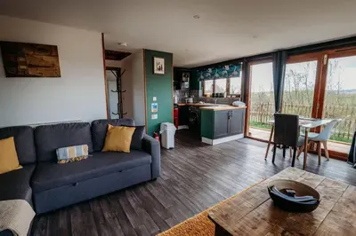 a living room with a blue couch and a kitchen at Woodpecker Lodge- A Pet Friendly Rural Retreat in Callington