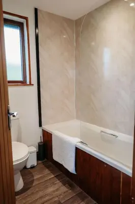 a bathroom with a bath tub and a toilet at Woodpecker Lodge- A Pet Friendly Rural Retreat in Callington
