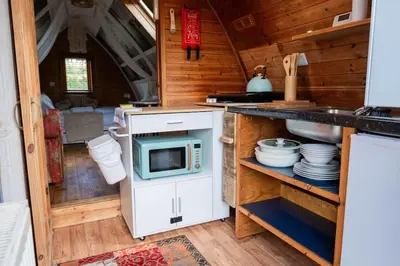 a kitchen with a stove and a microwave at Robin Nest - Cosy Shepherd's Hut Hideaway in Callington