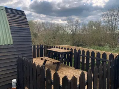 a picnic table on a wooden deck with a fence at Robin Nest - Cosy Shepherd's Hut Hideaway in Callington