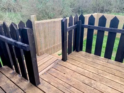 a wooden fence next to a wooden deck at Robin Nest - Cosy Shepherd's Hut Hideaway in Callington