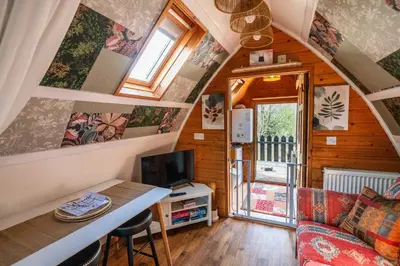 a living room with a couch and a table in a tiny house at Robin Nest - Cosy Shepherd's Hut Hideaway in Callington