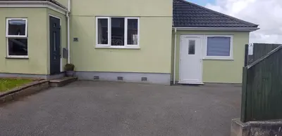 a yellow house with a white door and a fence at Self contained annex in Bodmin