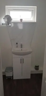 a white bathroom with a sink and a window at Self contained annex in Bodmin